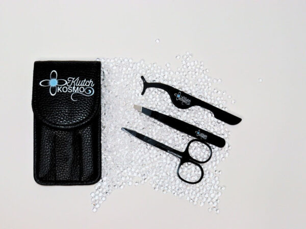 Klutch Kosmo luxury lash tool kit with precision tweezers, scissors, and applicator, displayed on sparkling crystals.